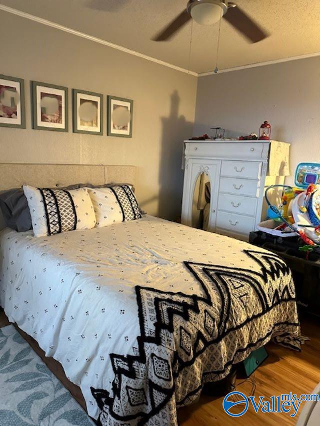 bedroom featuring a textured ceiling, ornamental molding, wood finished floors, and a ceiling fan