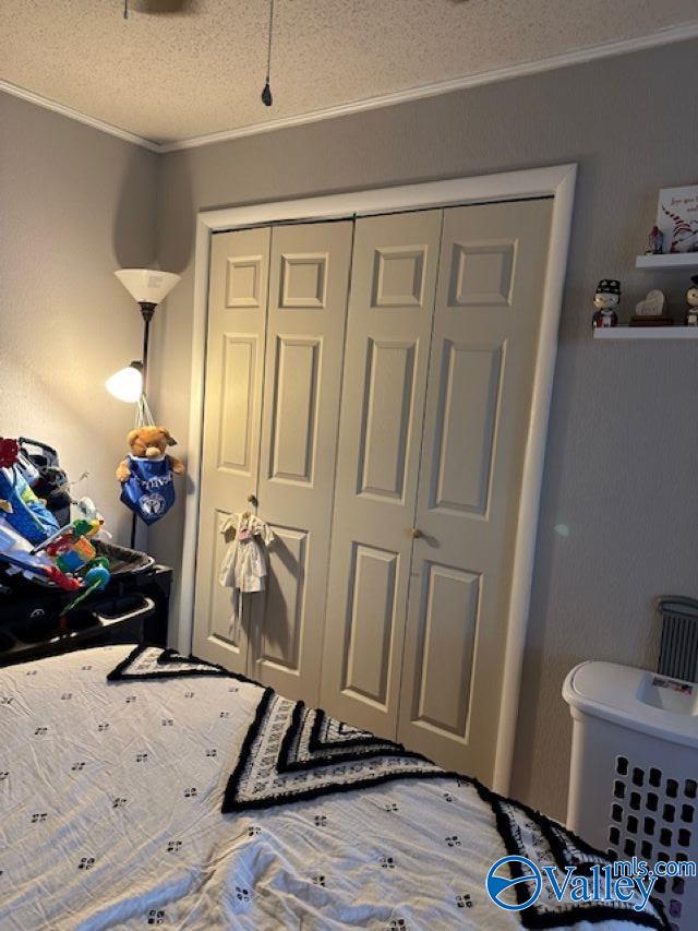 bedroom featuring crown molding, a textured ceiling, and a closet