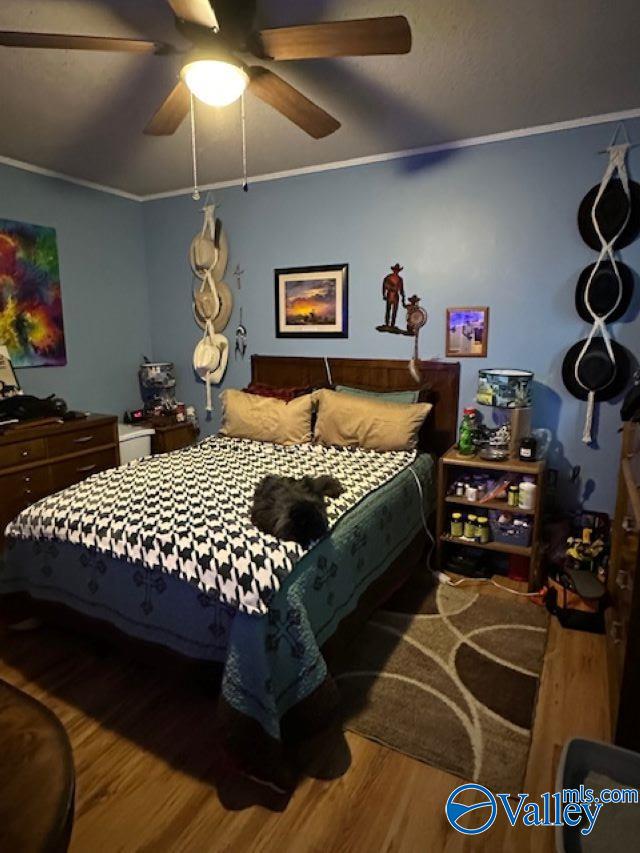 bedroom featuring ceiling fan, ornamental molding, and wood finished floors