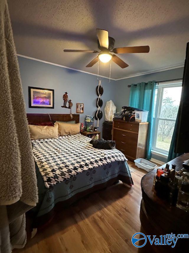 bedroom featuring a textured ceiling, wood finished floors, a ceiling fan, and crown molding