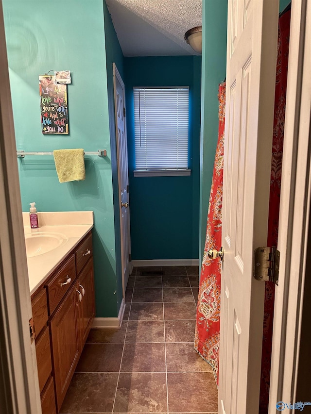 full bath featuring tile patterned flooring, a textured ceiling, vanity, and baseboards