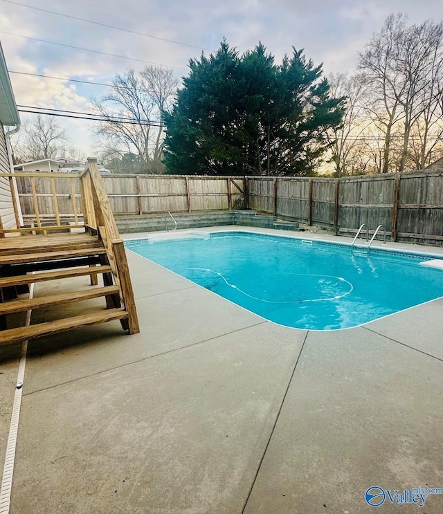 view of swimming pool featuring a fenced in pool, a patio, a fenced backyard, a wooden deck, and a diving board