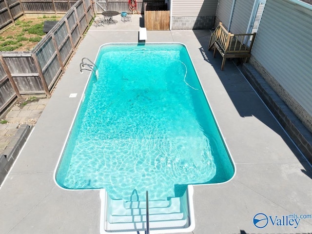view of pool featuring a fenced in pool, a patio, a fenced backyard, and a diving board