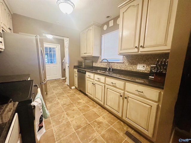 kitchen featuring dark countertops, visible vents, backsplash, stainless steel appliances, and a sink