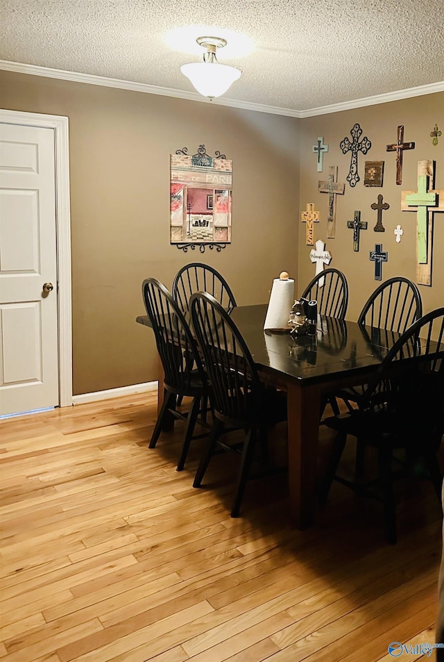 dining area with a textured ceiling, ornamental molding, and light wood finished floors