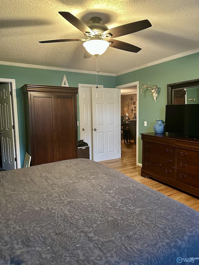 unfurnished bedroom with ceiling fan, light wood-type flooring, a textured ceiling, and ornamental molding