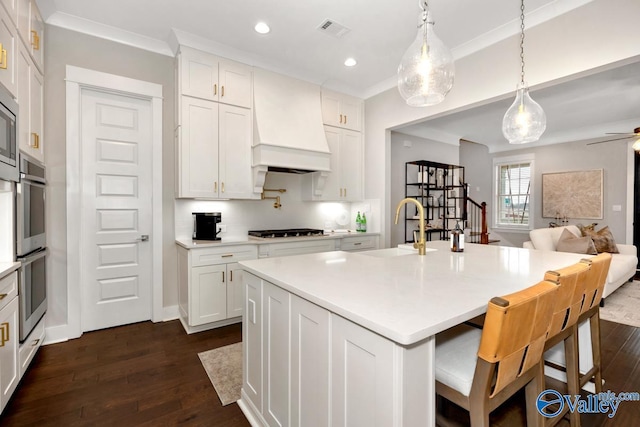 kitchen featuring sink, an island with sink, custom exhaust hood, and white cabinets