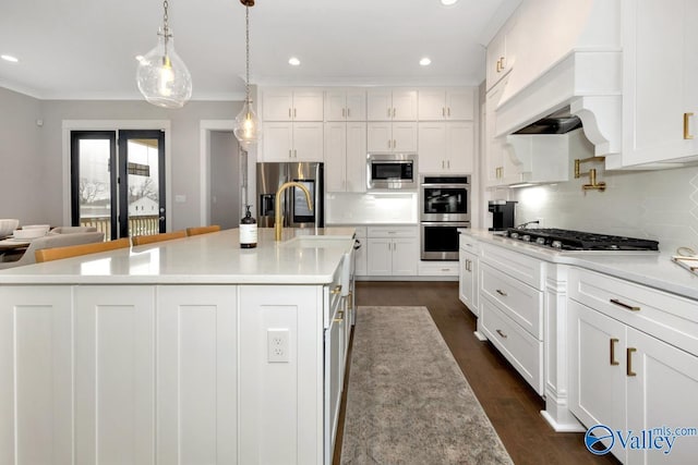 kitchen featuring a large island, pendant lighting, stainless steel appliances, and white cabinets