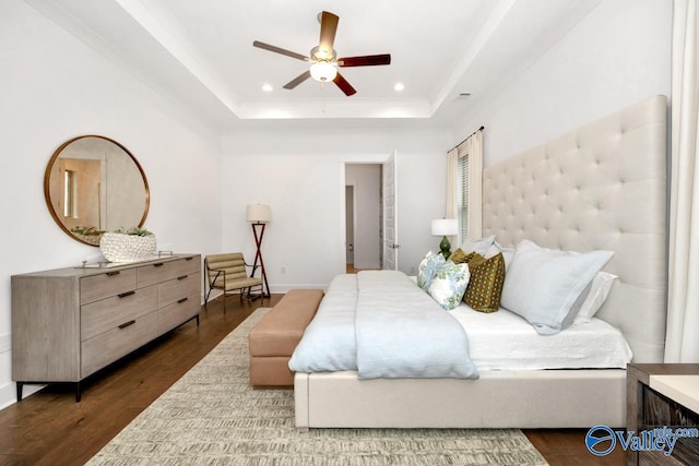 bedroom featuring ceiling fan, dark hardwood / wood-style flooring, and a tray ceiling