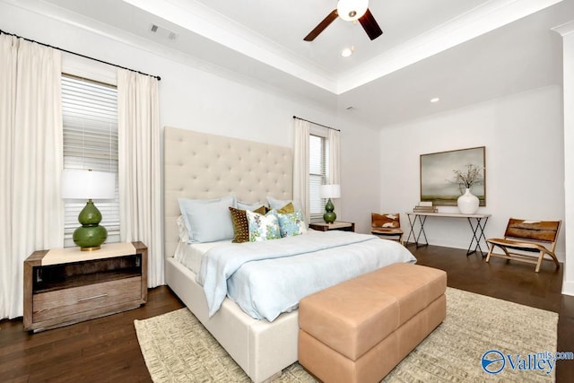 bedroom featuring a tray ceiling, dark wood-type flooring, ornamental molding, and ceiling fan