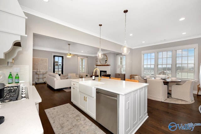 kitchen with pendant lighting, sink, white cabinets, a kitchen island with sink, and stainless steel appliances