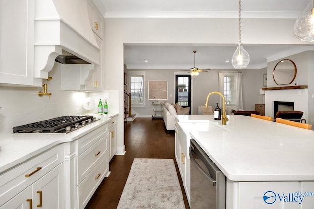 kitchen featuring a fireplace, decorative light fixtures, white cabinetry, a kitchen island with sink, and stainless steel appliances