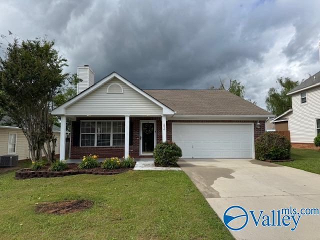 ranch-style house featuring brick siding, an attached garage, driveway, and cooling unit