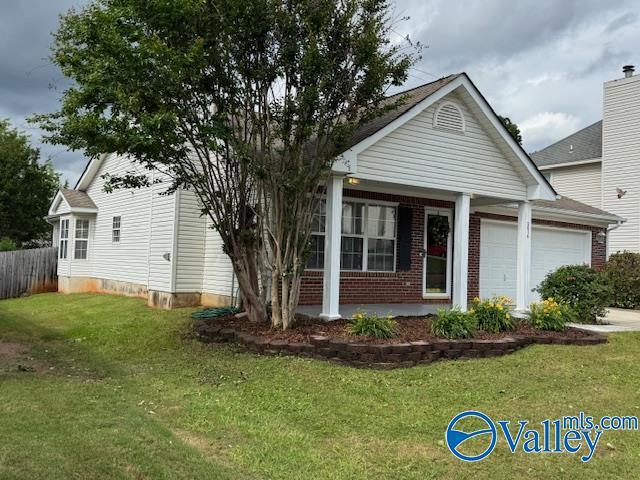 view of front of house with a garage, fence, a front lawn, and brick siding