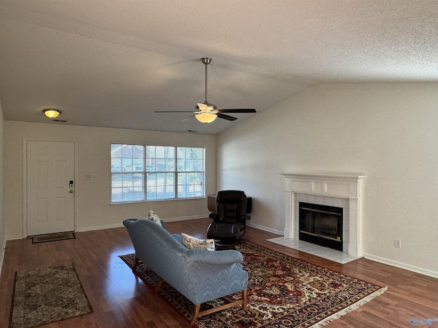 living area featuring ceiling fan, a fireplace, wood finished floors, baseboards, and lofted ceiling