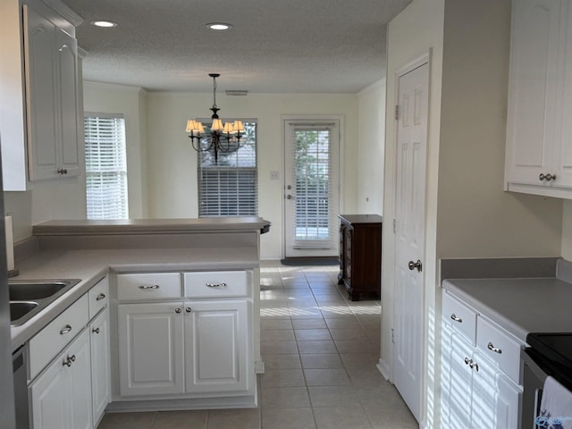 kitchen featuring a peninsula, white cabinetry, a chandelier, a sink, and light tile patterned floors
