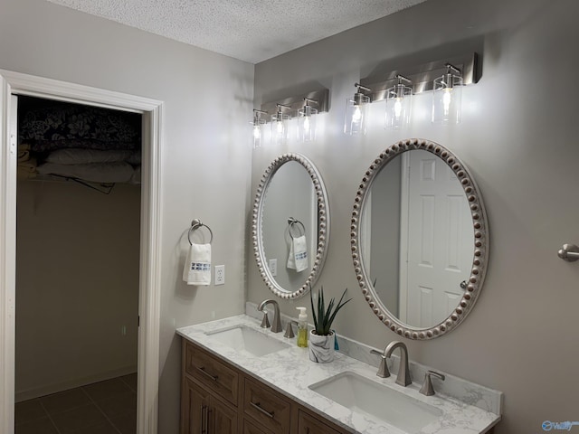 full bath featuring a sink, tile patterned flooring, double vanity, and a textured ceiling