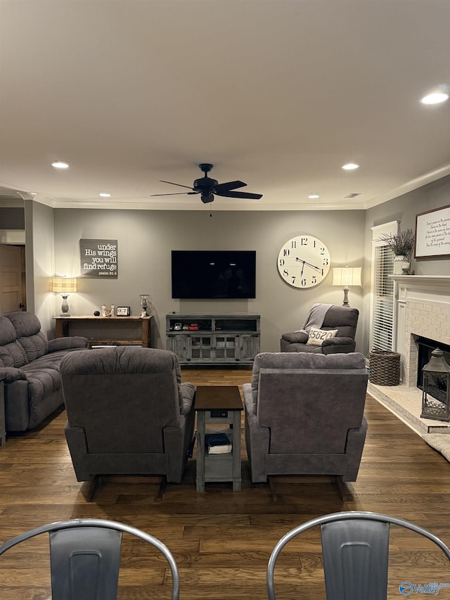 living room featuring dark hardwood / wood-style flooring, ornamental molding, ceiling fan, and a fireplace