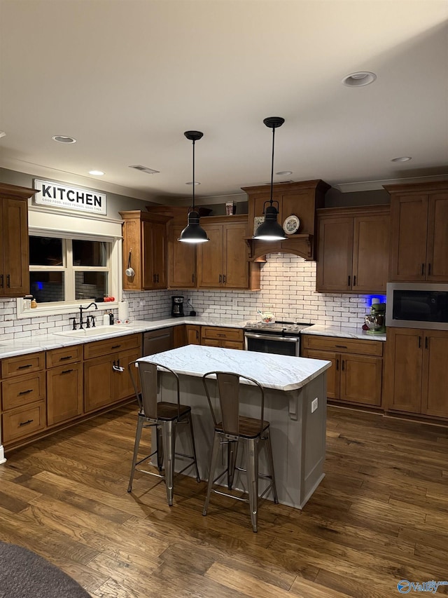 kitchen featuring built in microwave, a breakfast bar, stainless steel range with electric cooktop, a center island, and hanging light fixtures