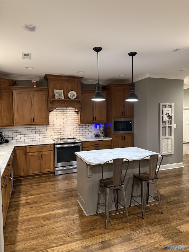 kitchen with a kitchen island, built in microwave, stainless steel range with electric cooktop, a kitchen breakfast bar, and hanging light fixtures