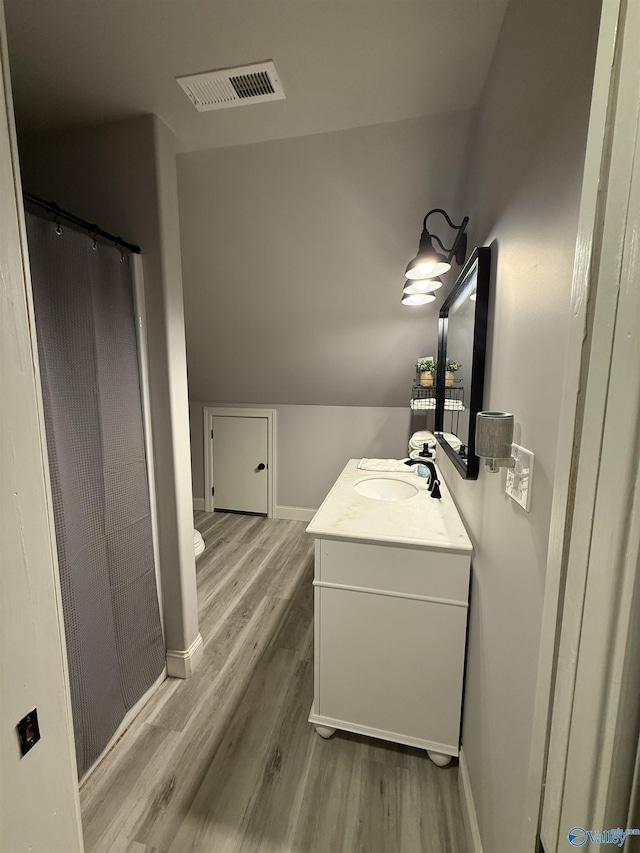 bathroom with vanity, lofted ceiling, wood-type flooring, and curtained shower