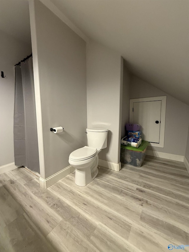 bathroom featuring vaulted ceiling, hardwood / wood-style floors, and toilet