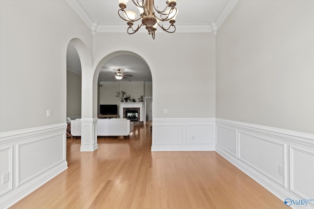 208 Honor Way, Madison, AL 35758 - unfurnished dining area with light wood-style flooring, crown molding, ceiling fan, a fireplace, and wainscoting