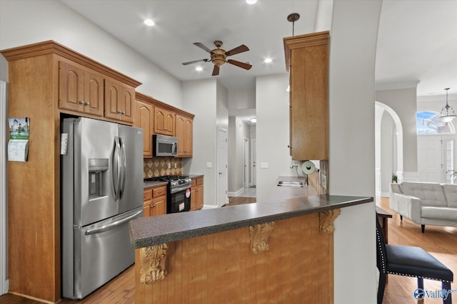 208 Honor Way, Madison, AL 35758 - kitchen with appliances with stainless steel finishes, a ceiling fan, wood finished floors, a breakfast bar, and dark countertops