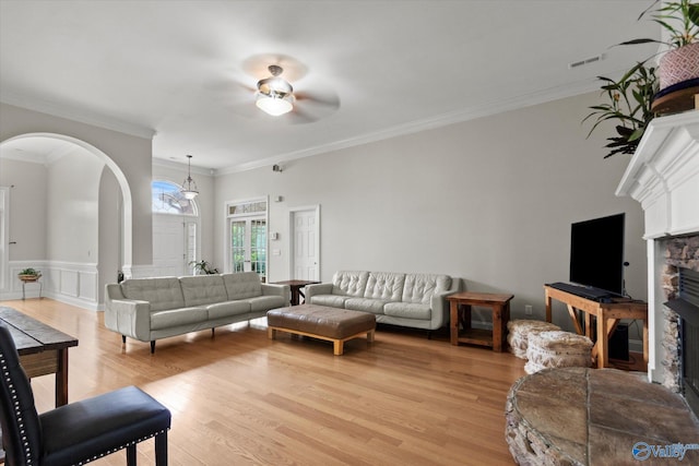 208 Honor Way, Madison, AL 35758 - living room featuring arched walkways, a stone fireplace, light wood finished floors, ceiling fan, and a wainscoted wall