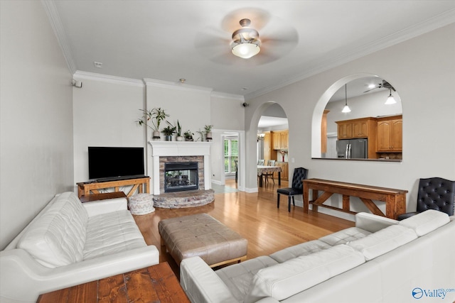 208 Honor Way, Madison, AL 35758 - living room with ceiling fan, light wood-style flooring, ornamental molding, arched walkways, and a stone fireplace