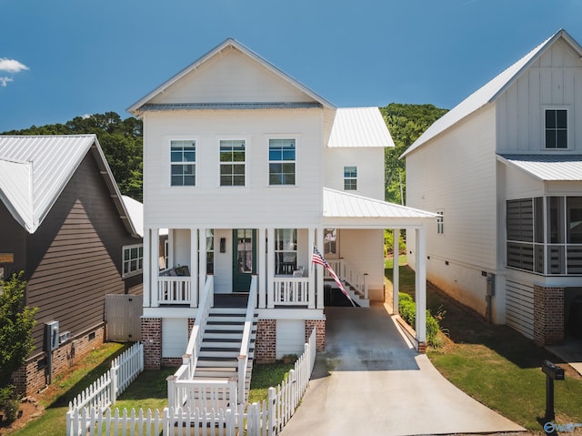 beach home with a fenced front yard, stairway, concrete driveway, covered porch, and crawl space
