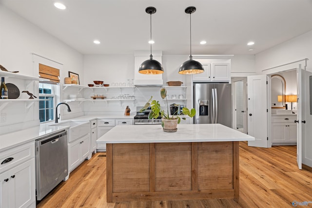 kitchen with a sink, stainless steel appliances, light countertops, and open shelves