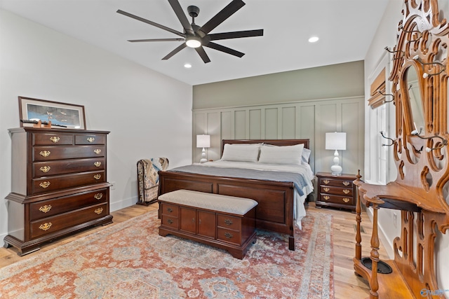 bedroom featuring light wood finished floors, a decorative wall, recessed lighting, and a ceiling fan