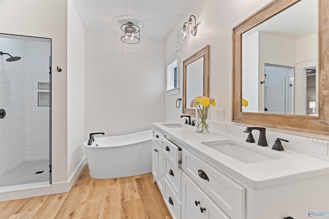 full bath featuring a freestanding bath, wood finished floors, a stall shower, and a sink