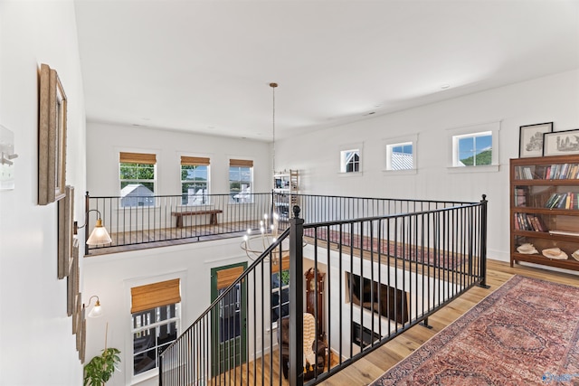 corridor with an inviting chandelier and wood finished floors