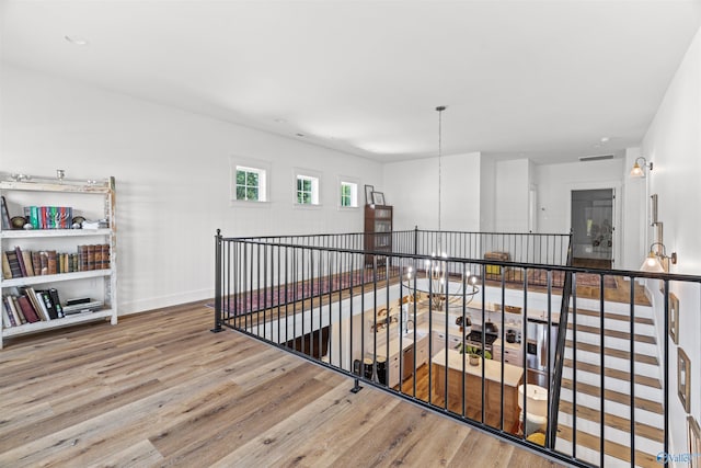 hallway with an upstairs landing, baseboards, and wood finished floors