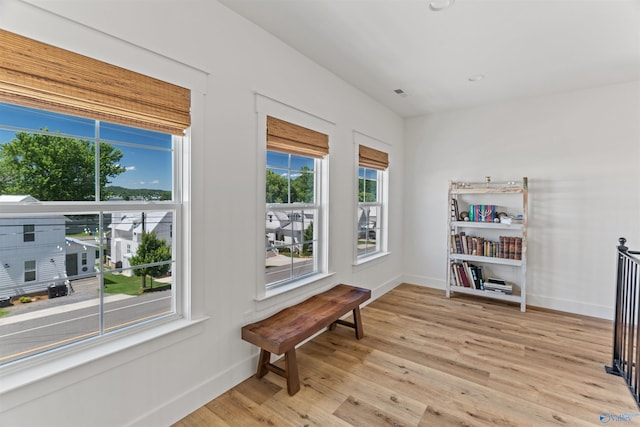 sitting room featuring visible vents, light wood-style floors, and baseboards