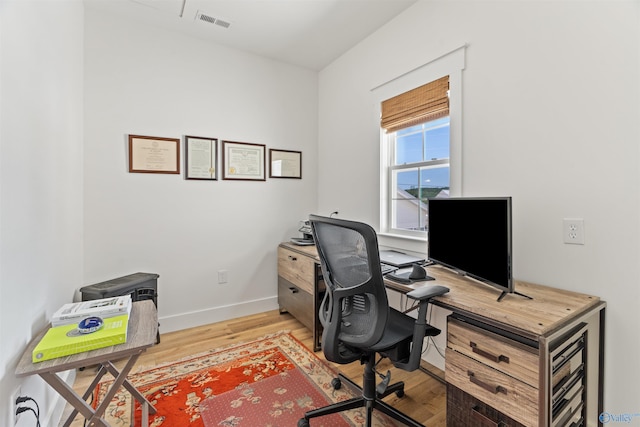 office space with wood finished floors, visible vents, and baseboards