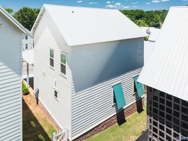 view of side of home featuring a lawn and metal roof