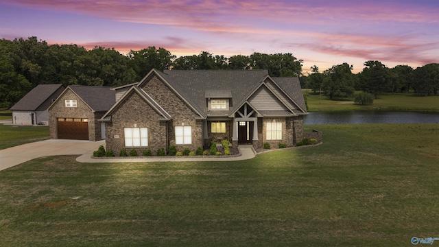 view of front of house with a water view, concrete driveway, a front yard, and stone siding