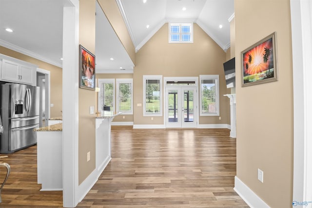 entrance foyer with crown molding, baseboards, and light wood-type flooring