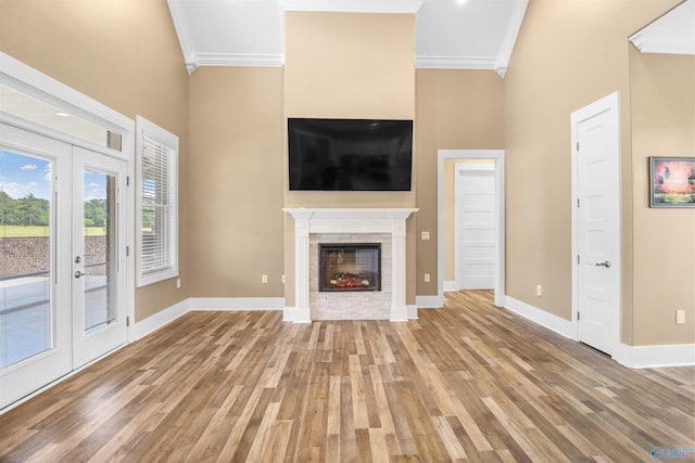 unfurnished living room featuring crown molding, baseboards, a high ceiling, and wood finished floors