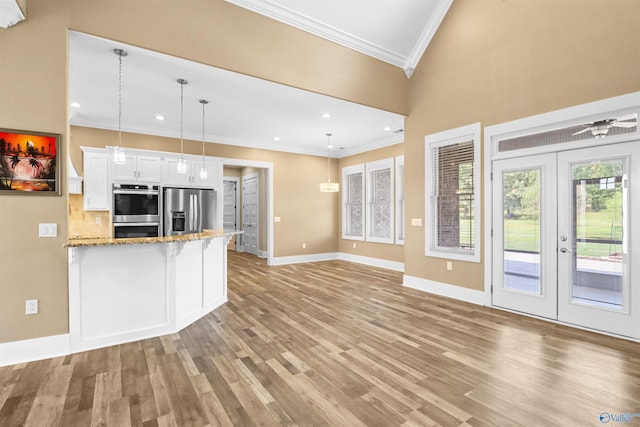 kitchen with light stone countertops, stainless steel appliances, white cabinetry, light wood-type flooring, and ornamental molding