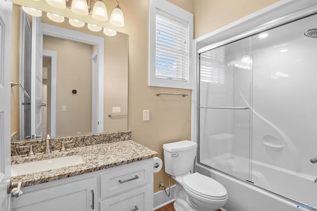 full bath with vanity, bath / shower combo with glass door, and toilet