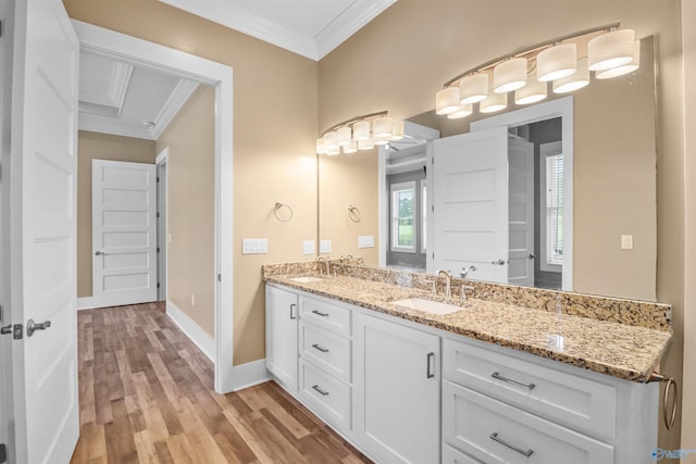 full bath featuring double vanity, ornamental molding, a sink, and wood finished floors