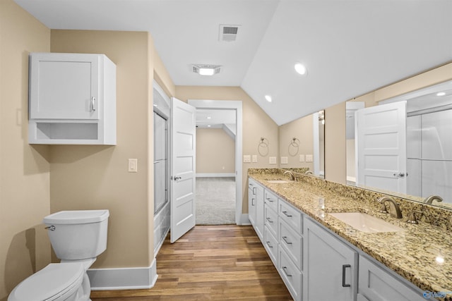 bathroom with a sink, toilet, wood finished floors, and visible vents