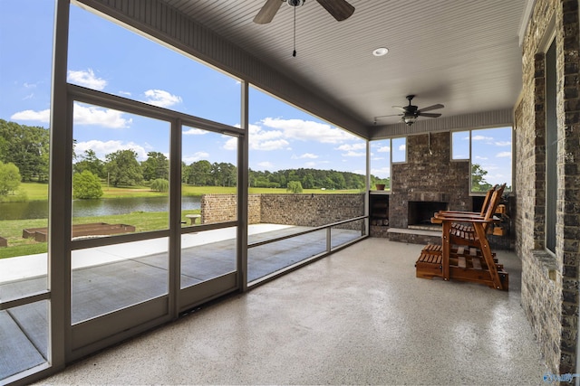 sunroom with an outdoor stone fireplace and ceiling fan