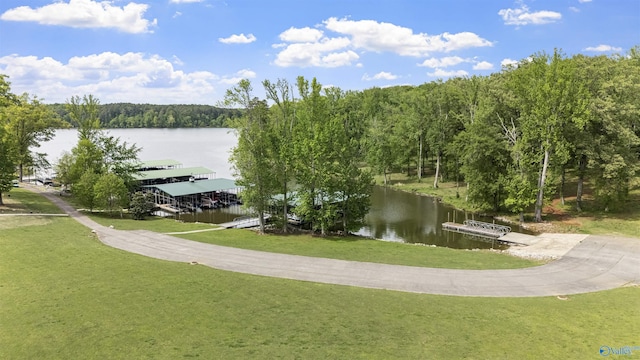 view of home's community with a yard, a water view, and a forest view