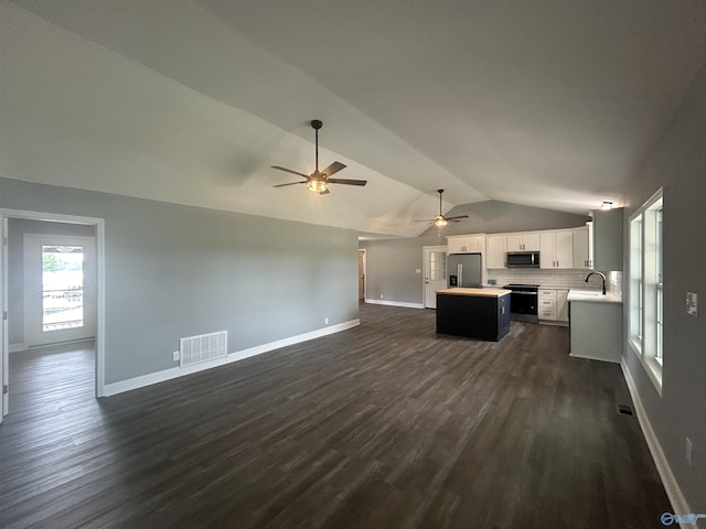 unfurnished living room with a sink, visible vents, baseboards, vaulted ceiling, and dark wood-style floors