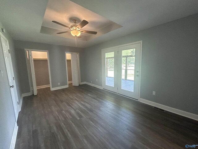 unfurnished bedroom featuring dark wood-type flooring, a raised ceiling, and baseboards